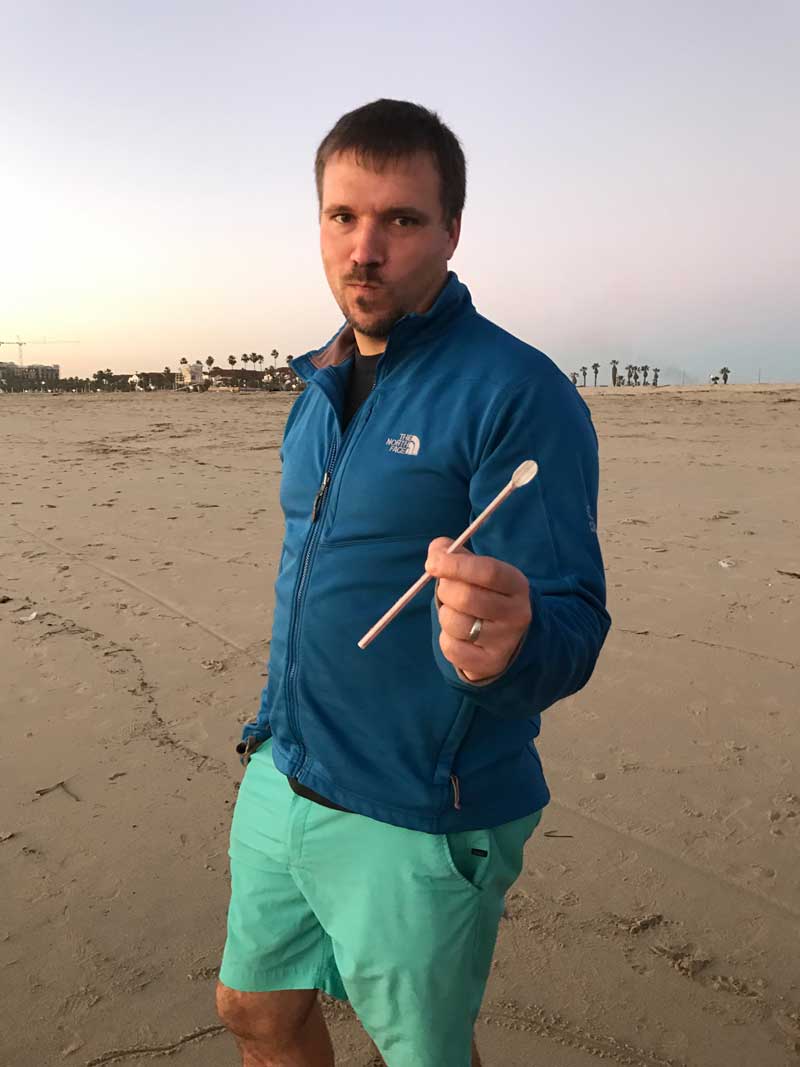 Man holding up plastic straw pollution at the beach